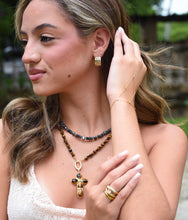 Load image into Gallery viewer, Model wearing Sienna wide 14K gold-filled hoop earrings with sculptural wave details.

